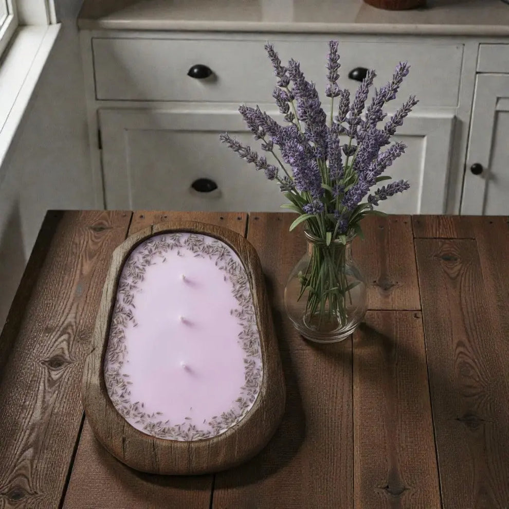 Light Purple candle with lavender flowers on a wooden table next to a vase of lavender.